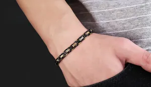 Gros plan d'un bracelet byzantin bicolore noir et or en acier inoxydable sur poignet homme