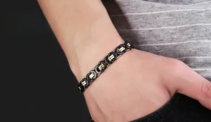Détail d'un bracelet pour homme en acier titane noir et or sur poignet avec maillons