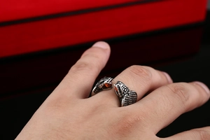 Macro detail of men's titanium steel dragon ring with intricate scales and red gemstones