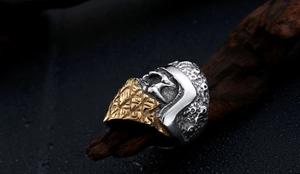 Macro detail of men's warrior helmet ring in gold and silver steel on wood