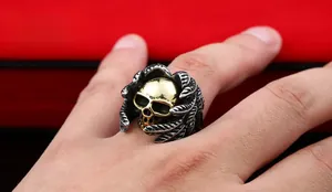 Macro shot of stainless steel wing ring with a gold skull centerpiece on red background