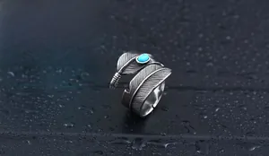 Close-up of vintage feather ring with turquoise stone inlay on a wet surface