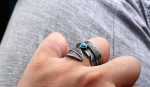 Detailed view of vintage feather ring with turquoise stone inlay and oxidized metal texture
