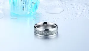 Macro shot of titanium steel ring with grey carbon fiber inlay on wet blue surface