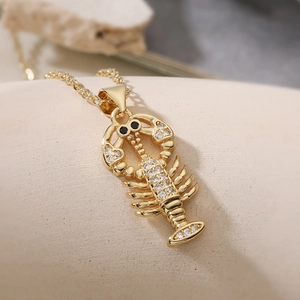 Dettaglio macro della collana con ciondolo aragosta dorata e zirconi incastonati
