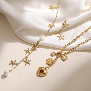 Collier perles étoile de mer dorée et pendentif cœur rouge sur fond de tissu en soie