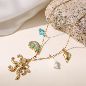 Golden octopus and seashell ocean-themed necklace with blue stones on white fabric