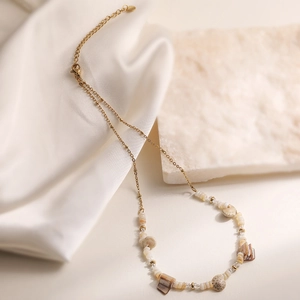 Collier en acier inoxydable doré avec perles de coquillage sur fond de pierre naturelle