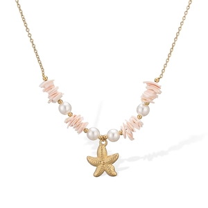 Detail of pink shell fragments and white pearls on a gold starfish pendant necklace