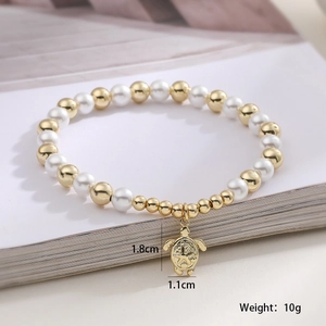 Close-up of pearl bracelet with gold sea turtle charm and engraved star patterns