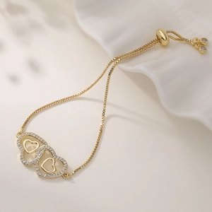 Elegant gold-tone box chain bracelet with interlocking zircon heart pendants and adjustable slider