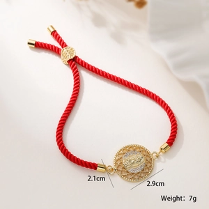 Detalle de pulsera roja con colgante de la Virgen María y circonitas doradas