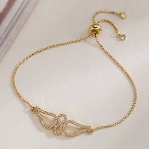 Detailed close-up of 18K gold plated wing pendant bracelet with sparkling zircon accents