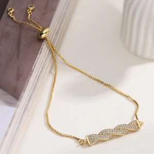 Detail of adjustable 18K gold plated zircon bracelet with twisted slider bar design