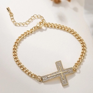 Détail d'un bracelet gourmette plaqué or 18 carats avec pendentif croix serti de zircons