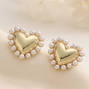Elegant 18K gold plated heart stud earrings with white pearl inlay on cream surface