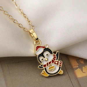 Golden Christmas penguin necklace with red hat and scarf on elegant white silk background