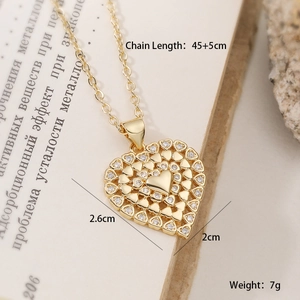 Detalle de un colgante de corazón bañado en oro de 18K con circonitas sobre un libro