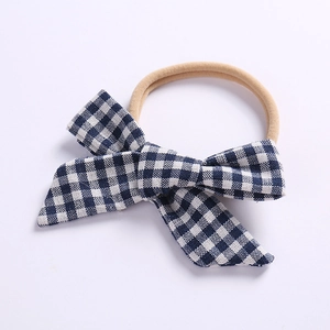 Detail von blau-schwarz karierter Stoffschleife auf beige elastischem Baby Stirnband