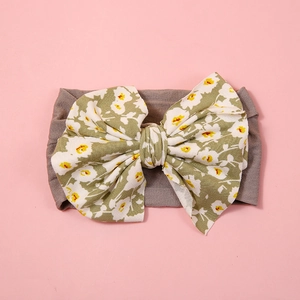Detail of baby headband with oversized floral bow and soft nylon fabric on pink background