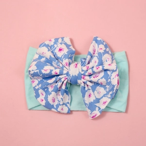 Close-up of baby headband with large blue floral bow on mint green elastic band