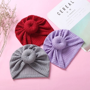 Detailed waffle knit texture of infant donut hats in burgundy, lavender and grey colors