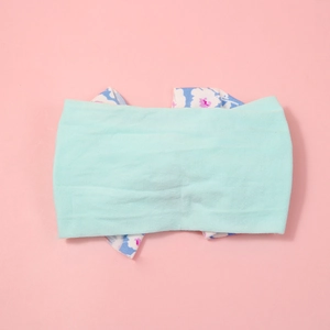 Detail of mint green nylon headband with blue floral fabric lining on pink background