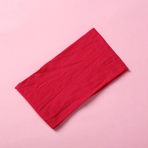 Detailed close-up of a vibrant red soft nylon baby headband on a light pink background
