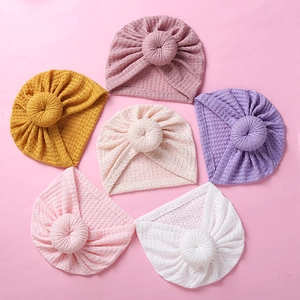 Flat lay of colorful baby waffle hats with donut knots in yellow, purple, and pink