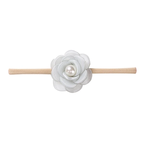 Detail of baby headband featuring a white satin camellia flower with pearl accent