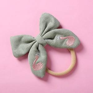 Détail du nœud tricoté vert avec broderie cygne rose et bandeau en nylon souple pour bébé