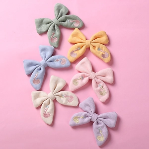 Gros plan détaillé de six barrettes noeuds brodées de cygnes aux couleurs pastel