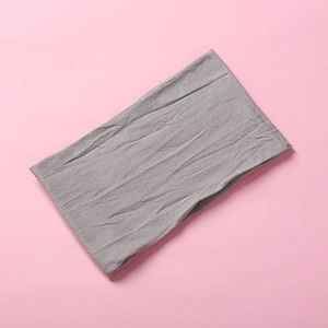 Detail view of a gray soft nylon baby headband with elastic wrinkled texture on pink background