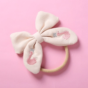 Détail du nœud brodé cygne sur un bandeau bébé en nylon souple avec texture gaufrée