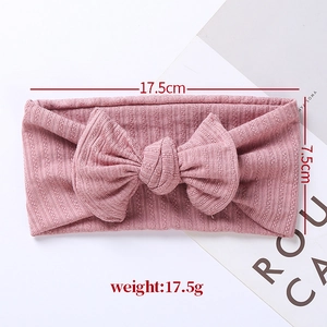 Pink jacquard knit baby headband with large bow detail and dimension measurements