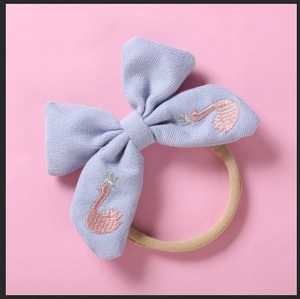Détail du bandeau bébé avec nœud lilas, broderie de cygne rose et ruban en nylon souple