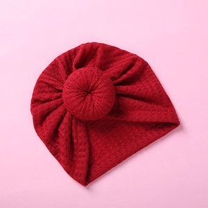 Detail view of red waffle fabric baby turban hat with a cute donut knot design