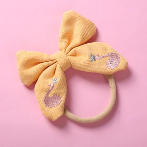 Détail du bandeau en nylon à nœud jaune avec broderie de cygne rose et couronne argentée