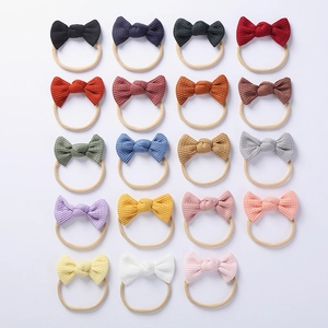 Flat lay display of 19 assorted colors of waffle texture baby bow headbands for infants