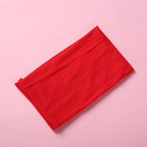 Detail view of a bright red soft nylon baby headband on a light pink background