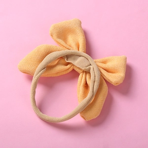 Détail du nœud en tissu orange doux et de la texture du bandeau en nylon pour bébé