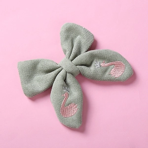 Détail d'une barrette nœud en coton vert avec broderie cygne rose et couronne