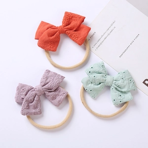 Dettaglio di tre fasce per neonati in nylon con ricami floreali su fiocchi di cotone