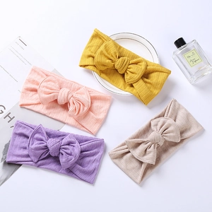 Flat lay detail of colorful jacquard knit baby headbands with large bows on white background