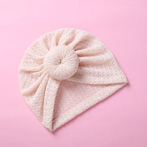 Detailed macro view showing the textured waffle knit fabric and soft donut knot of the pink hat