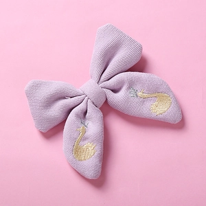 Détail d'une pince à cheveux nœud tricoté lilas avec broderie de cygne et couronne