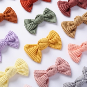 Detail showing various Morandi colored waffle knit bow hair clips for girls on grey background