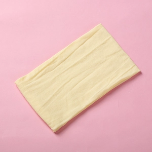 Macro shot of a light yellow nylon baby headband with vertical ribbed texture on pink background