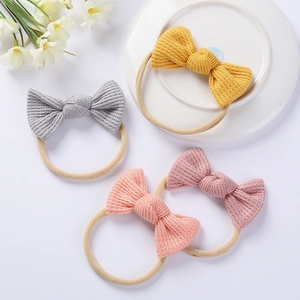 Set of four waffle knit baby bow headbands in yellow, grey, pink and red with soft nylon bands