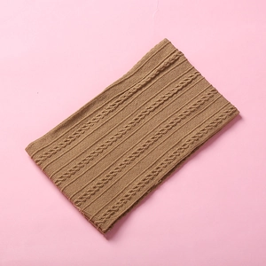 Detailed view of dark brown knitted baby headband with thick cable pattern texture